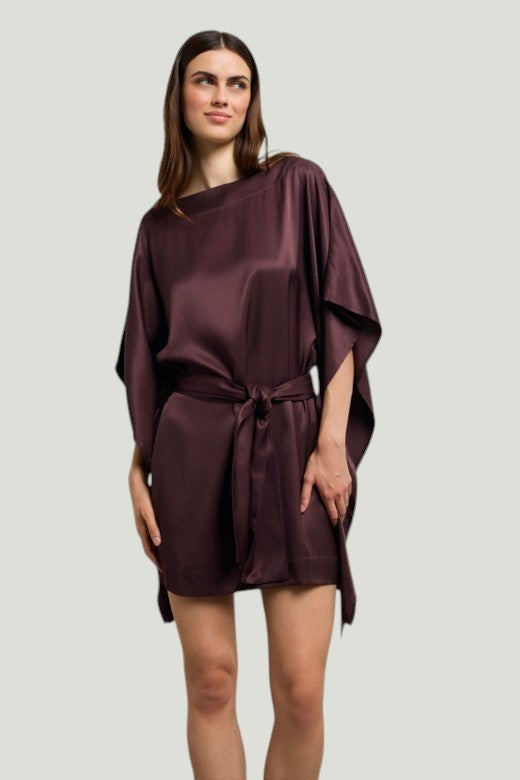 Model draagt een donkerpaarse Mademoiselle Ambitious Cartney korte jurk van viscose met wijde mouwen en ceintuur.