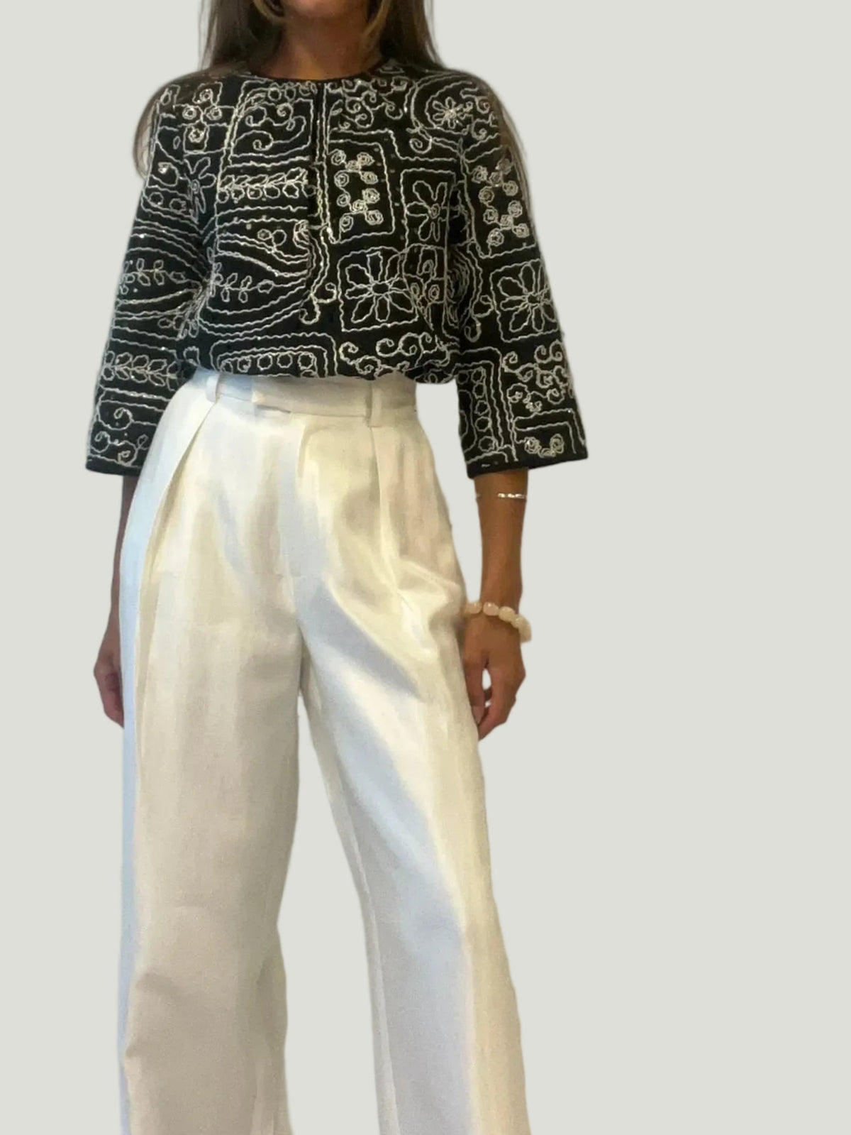 Model draagt Mademoiselle Ambitious Hanna blouse met zwart-wit borduurwerk en driekwartmouwen bij witte pantalon