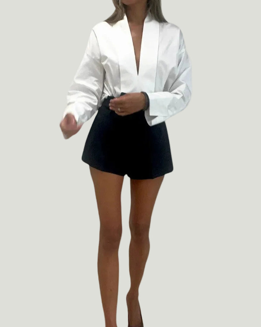 Model draagt de witte Mademoiselle Ambitious Mathilda blouse met diepe V-hals en brede manchetten in een casual look.