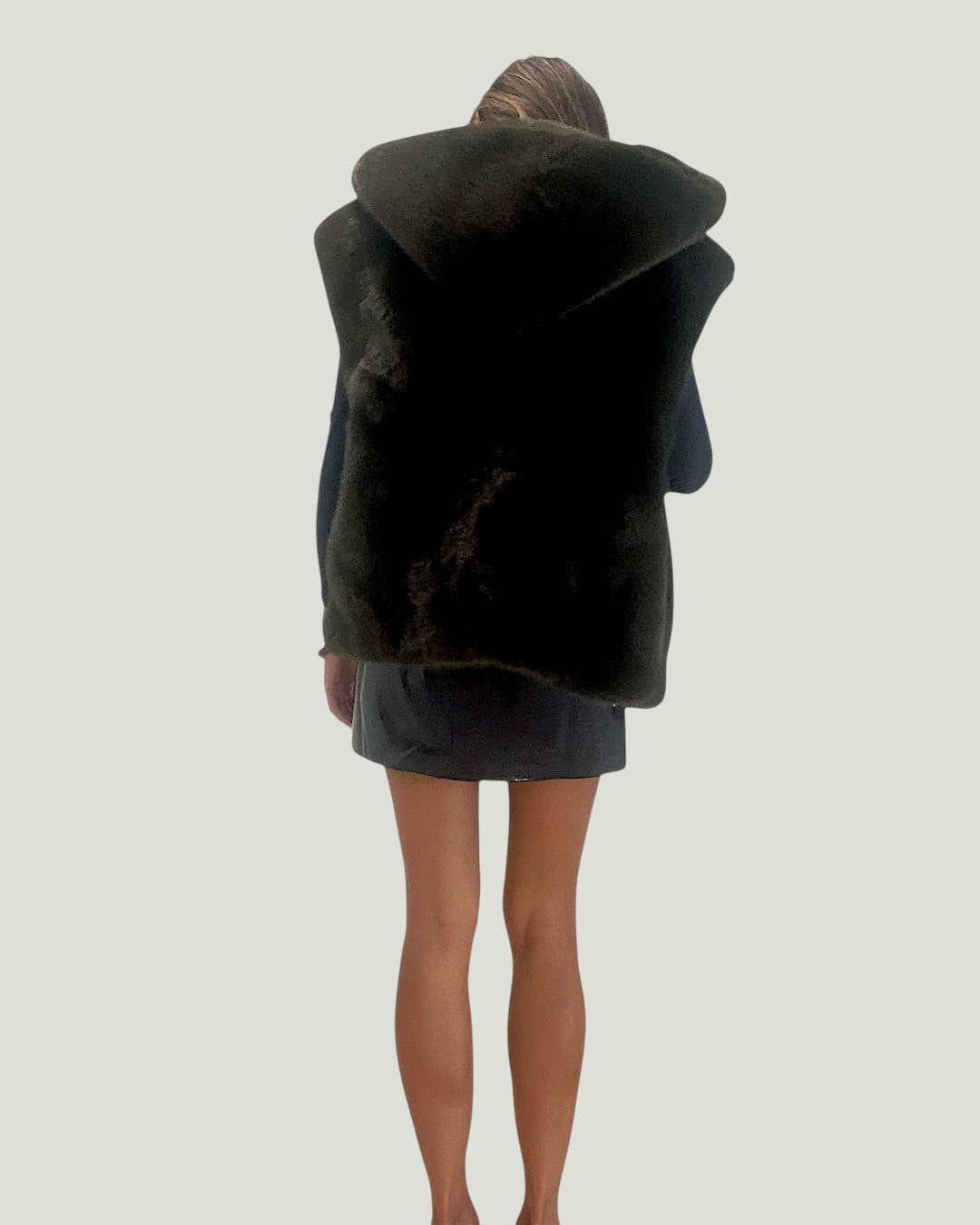 Mademoiselle Ambitious Pierre mouwloos jasje van zwart imitatiebont met capuchon, gedragen op de rug gezien.